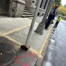 Fresh sidewalk near a building entrance with workers at the curb