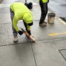 Crew member caulking a joint near the curb with a bucket nearby