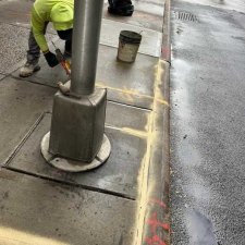 Worker sealing the joint beside a light pole base