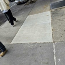 Broom-finished new slabs with edge borders next to a tree pit and worn old slabs